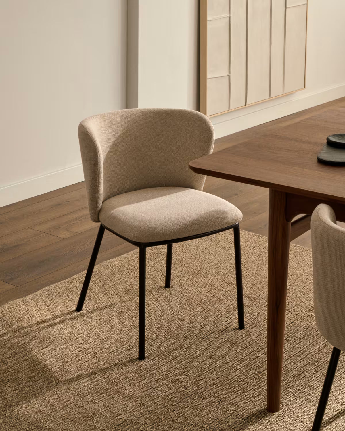 Ein Stuhl im Ciselia Beige Szenil Stoff mit einer schwarzen Basis